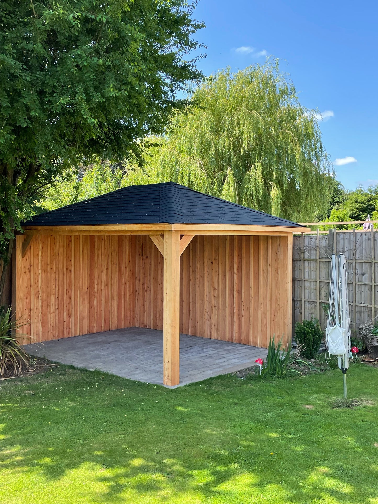 Wooden gazebo with cladding on block paving in a garden