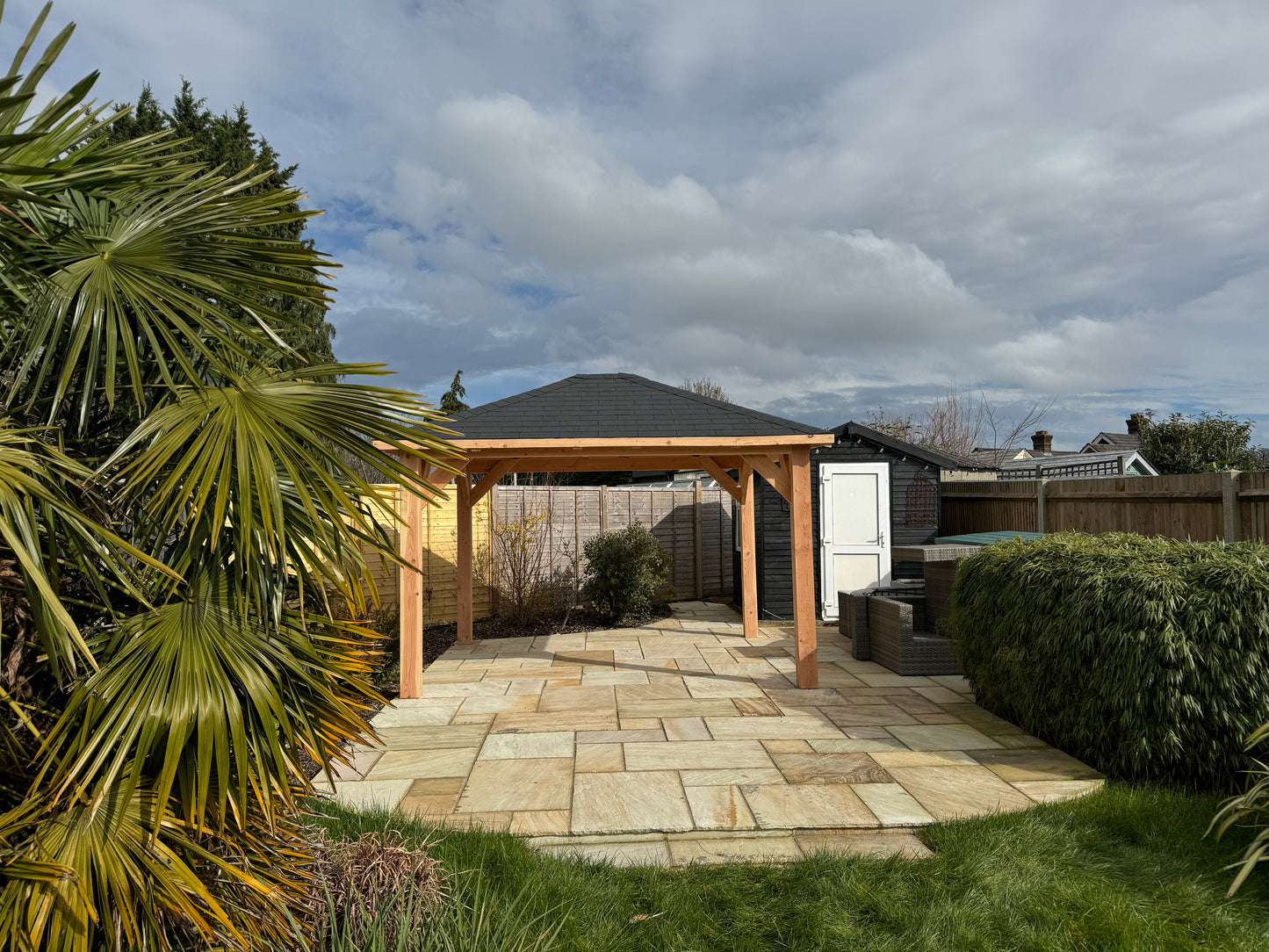 A chunky looking wooden gazebo with black felt shingles