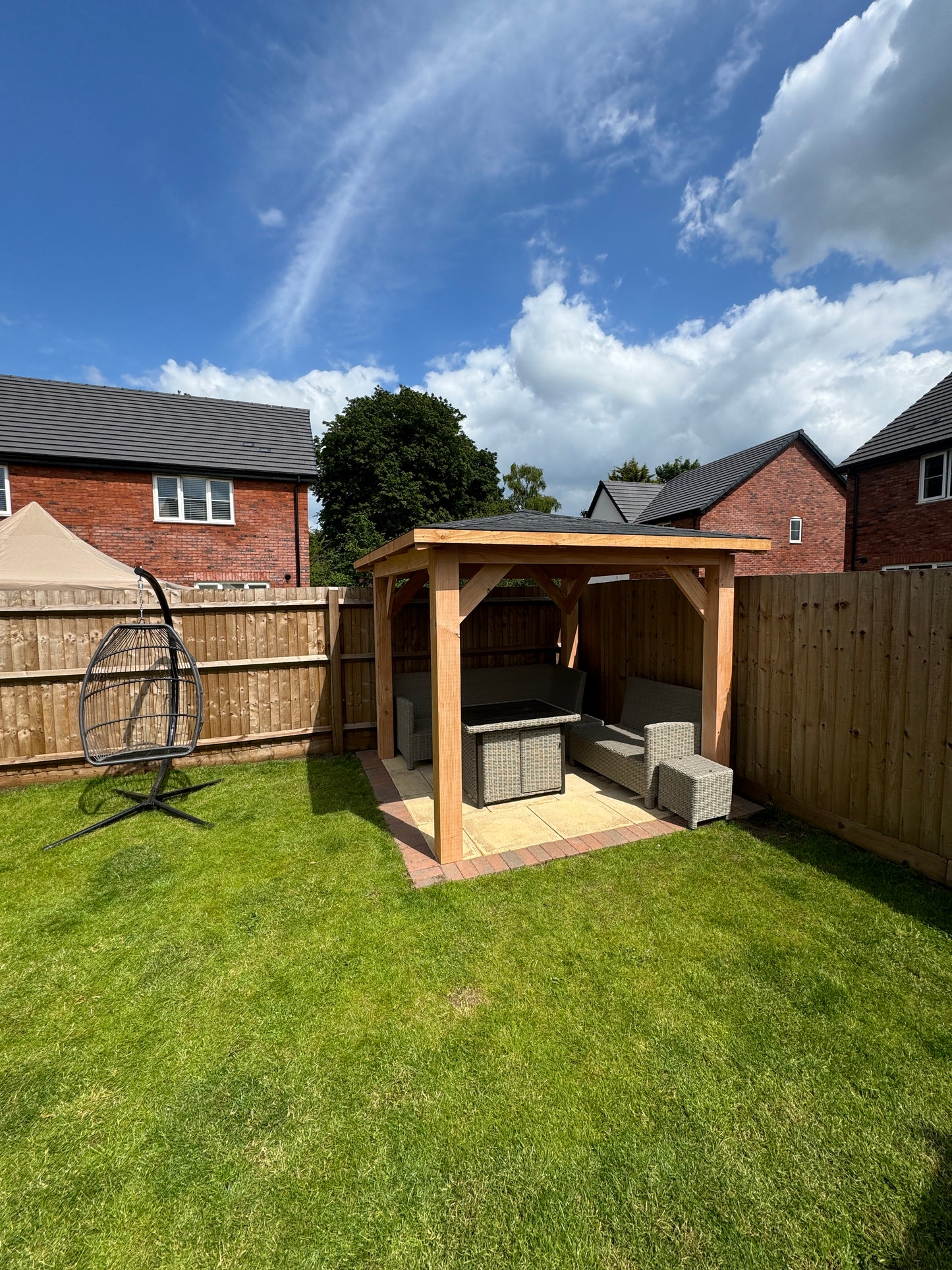Timber gazebo in a garden with furniture