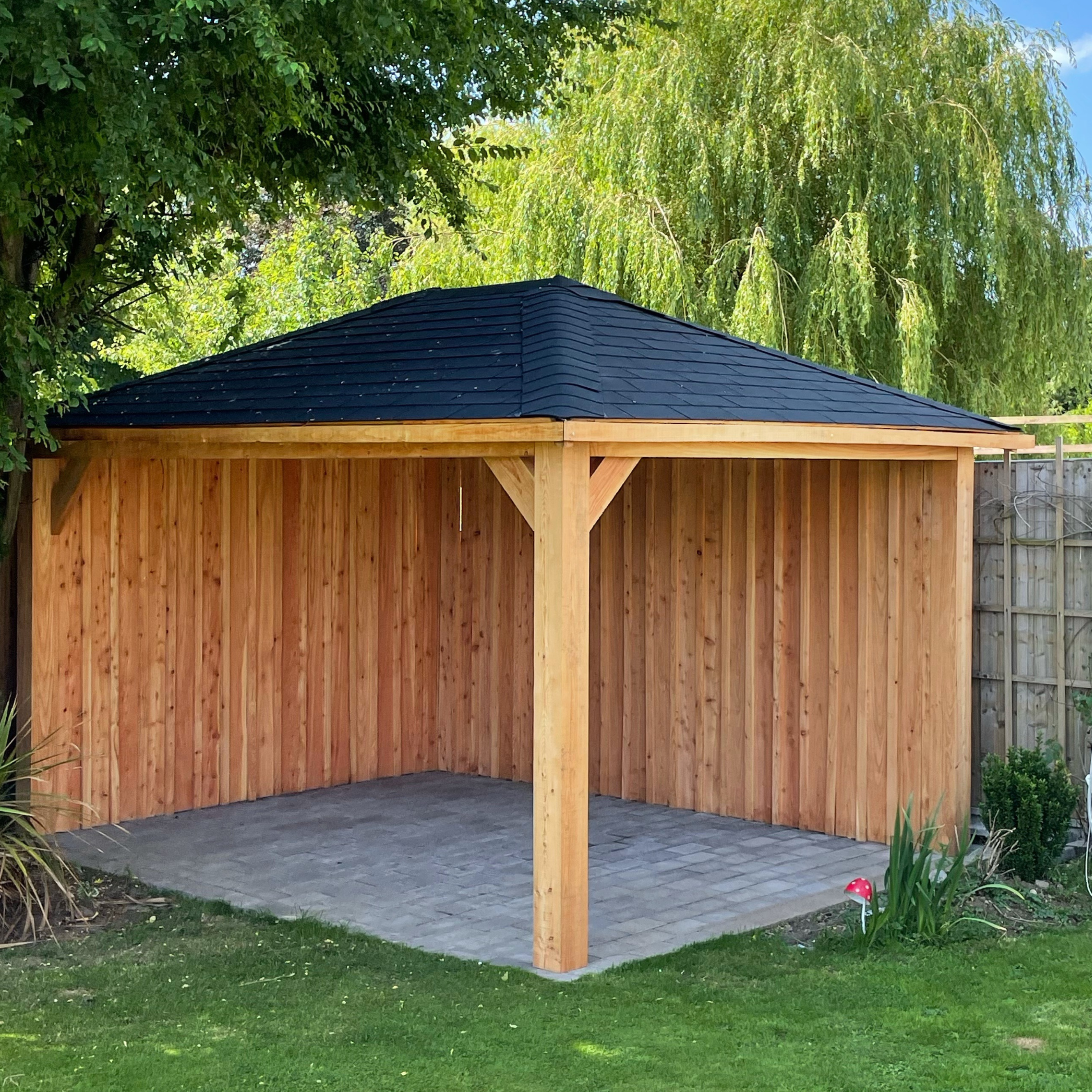 3.5m X 3m larch timber gazebo with board and batten cladding to two sides and black felt shingles