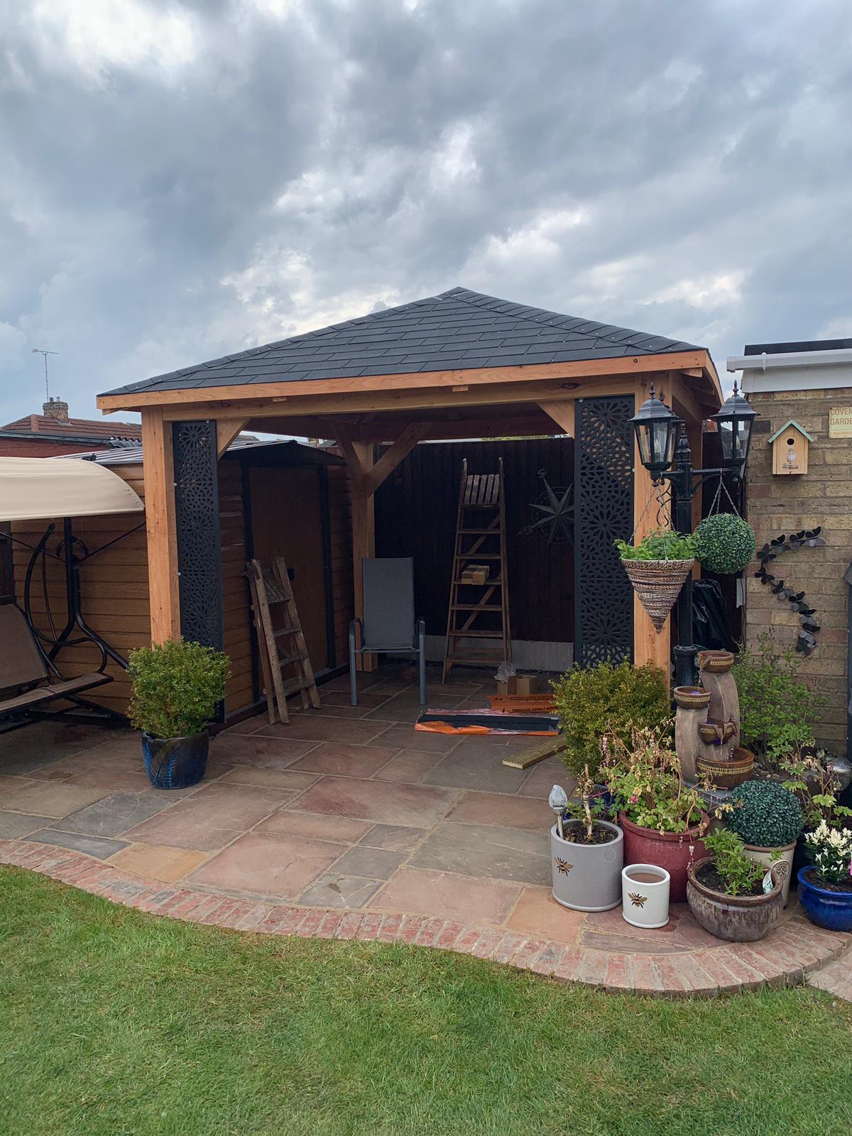 Garden gazebo with plants and outdoor furniture under a cloudy sky