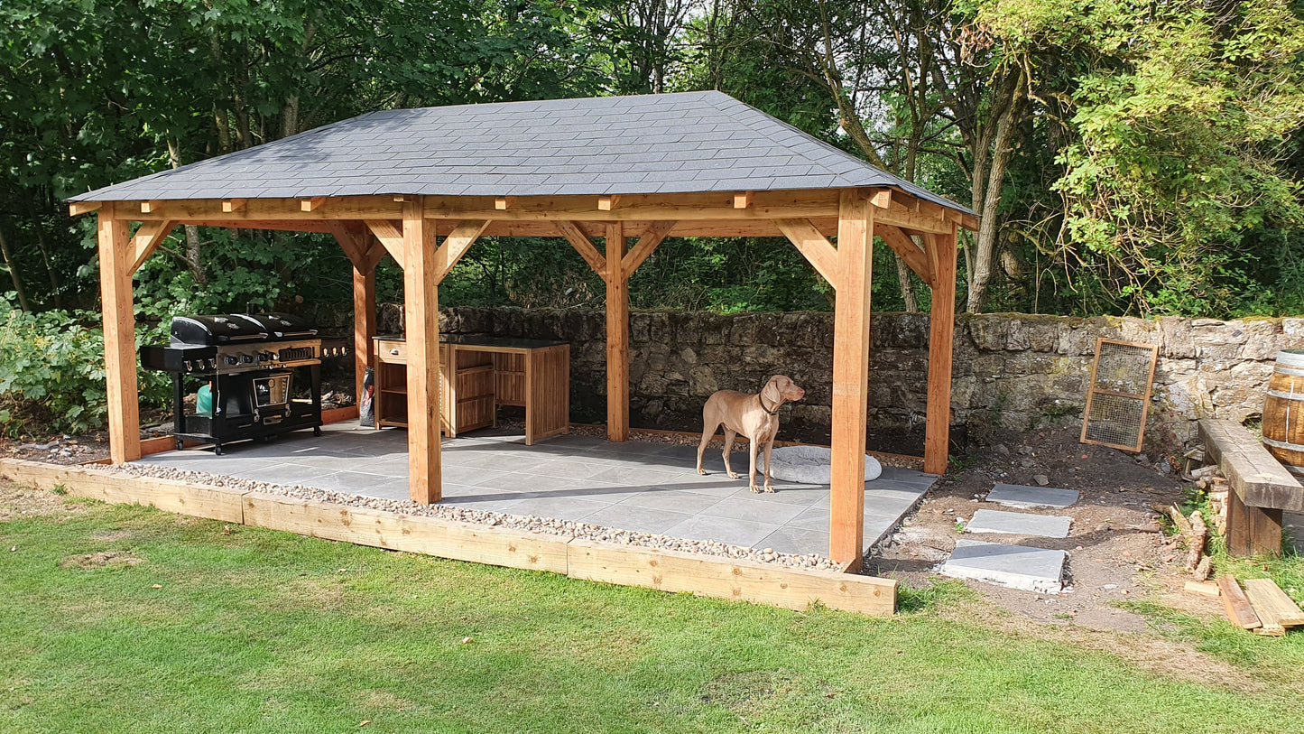 Wooden gazebo with a roof in a garden setting with a dog standing inside.