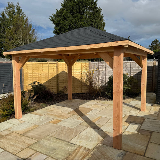 A beautiful wooden gazebo on a new patio set in front or fencing