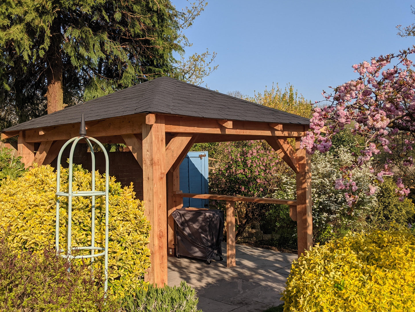 Wooden gazebo in a garden with trees and flowers